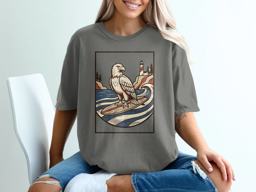 Eagle surfing with lighthouse and trees on a distressed graphic design tee.