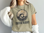 Tan t-shirt with circular graphic of wave and record, text "COASTLINE FREQUENCY".