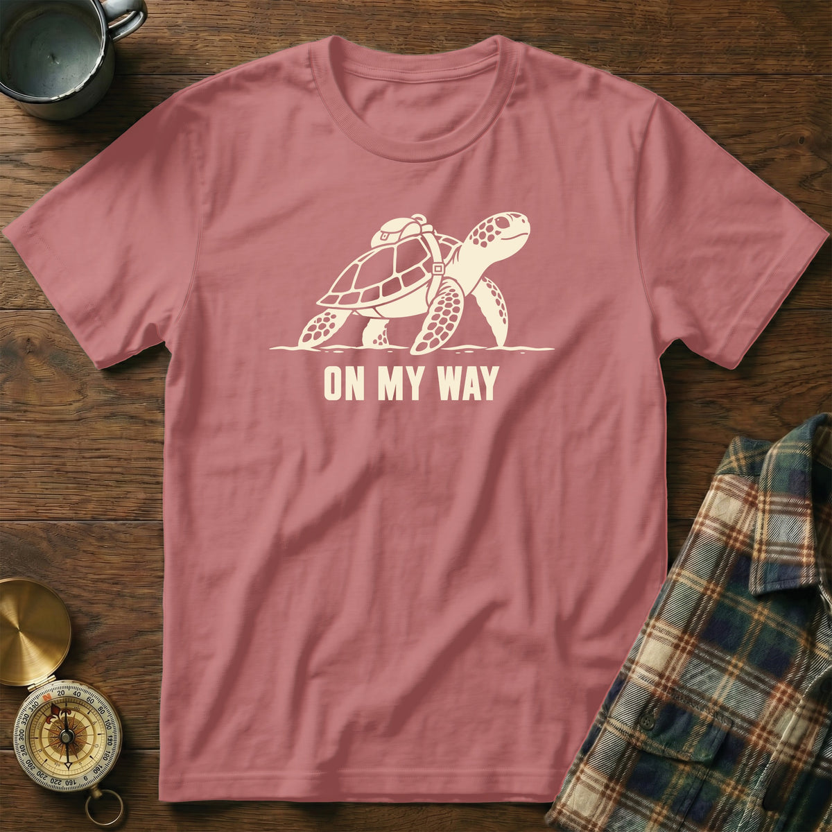 Pink t-shirt with a graphic of a turtle wearing a backpack and text "ON MY WAY".