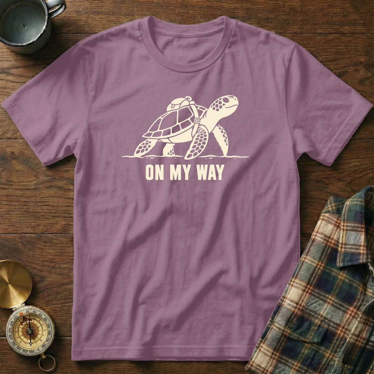Purple t-shirt with a graphic of a turtle carrying a backpack and the text "ON MY WAY."