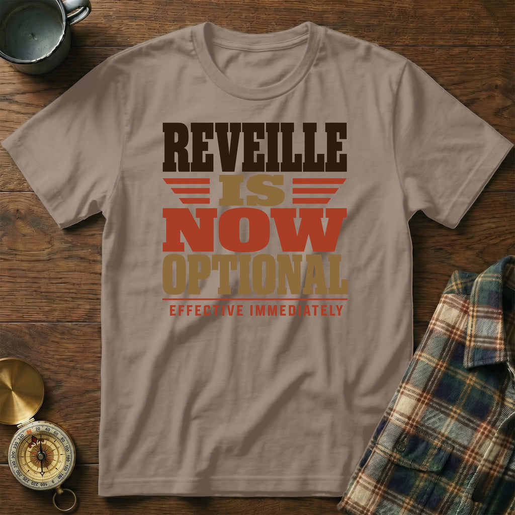 A taupe t-shirt featuring the text "Reveille is now optional, effective immediately" printed in brown, tan, and orange.