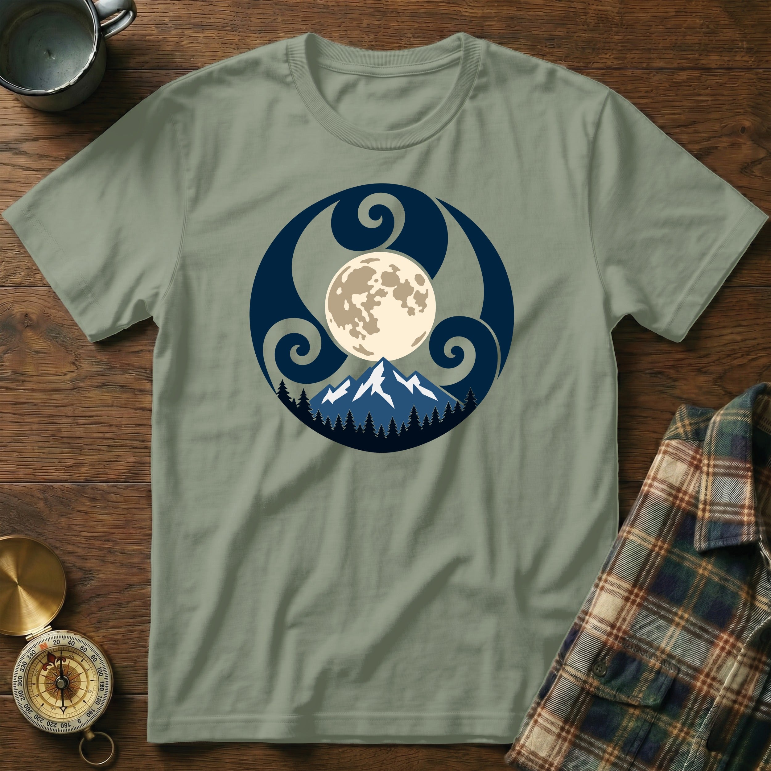 Green t-shirt with a circular design of a moon, mountains, and trees.
