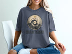 Dark grey t-shirt with a circular graphic of a vinyl record and a wave, reading "COASTLINE FREQUENCY".