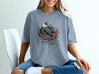 Bald eagle wearing sunglasses floats on inner tube with drink on blue shirt.