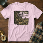 Pink t-shirt with Bigfoot illustration on rocky cliff overlooking the ocean.
