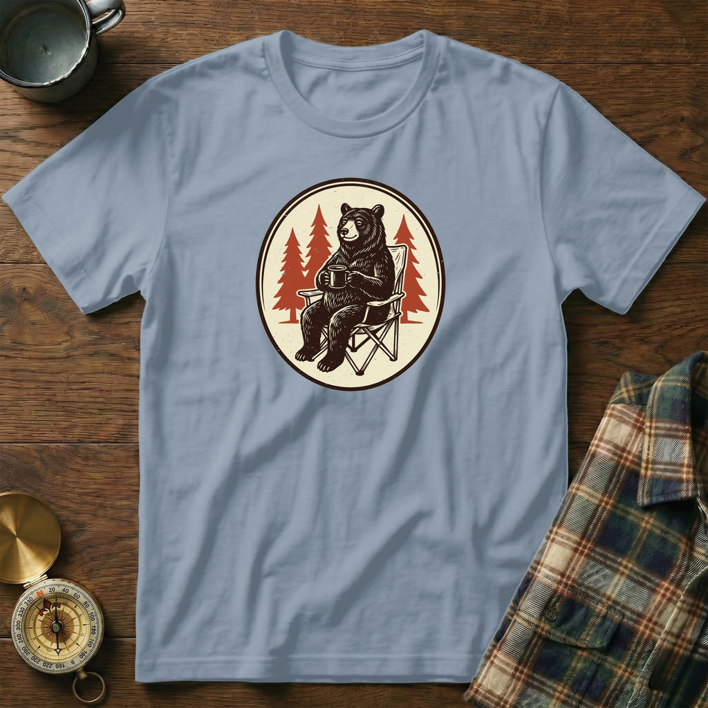 T-shirt with graphic of bear sitting in chair holding coffee mug, surrounded by trees.