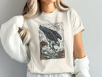 White t-shirt with woodcut-style osprey diving into waves graphic.