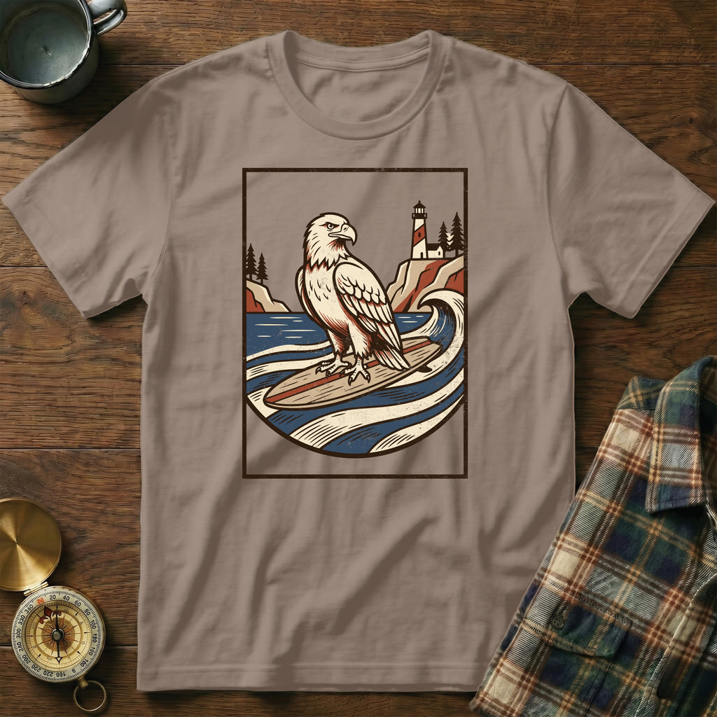T-shirt with graphic of eagle on surfboard in front of lighthouse.
