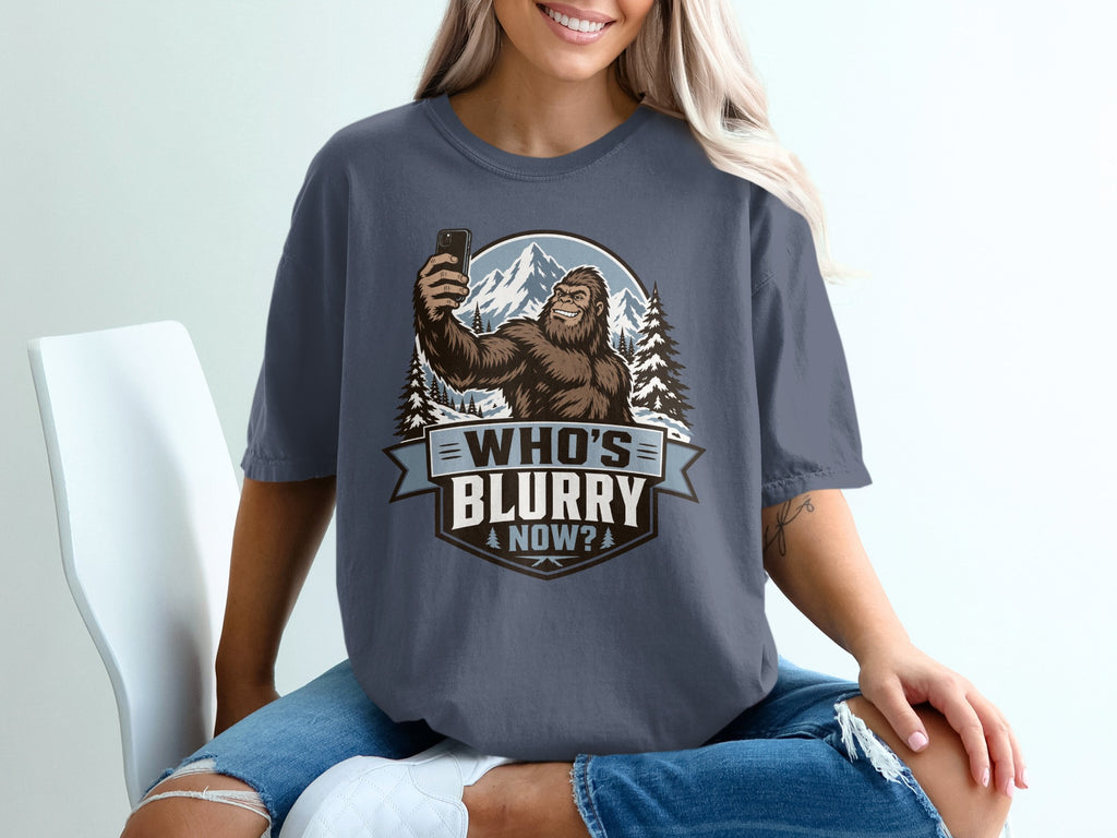 Bigfoot taking a selfie in snowy mountains with text "WHO'S BLURRY NOW?".