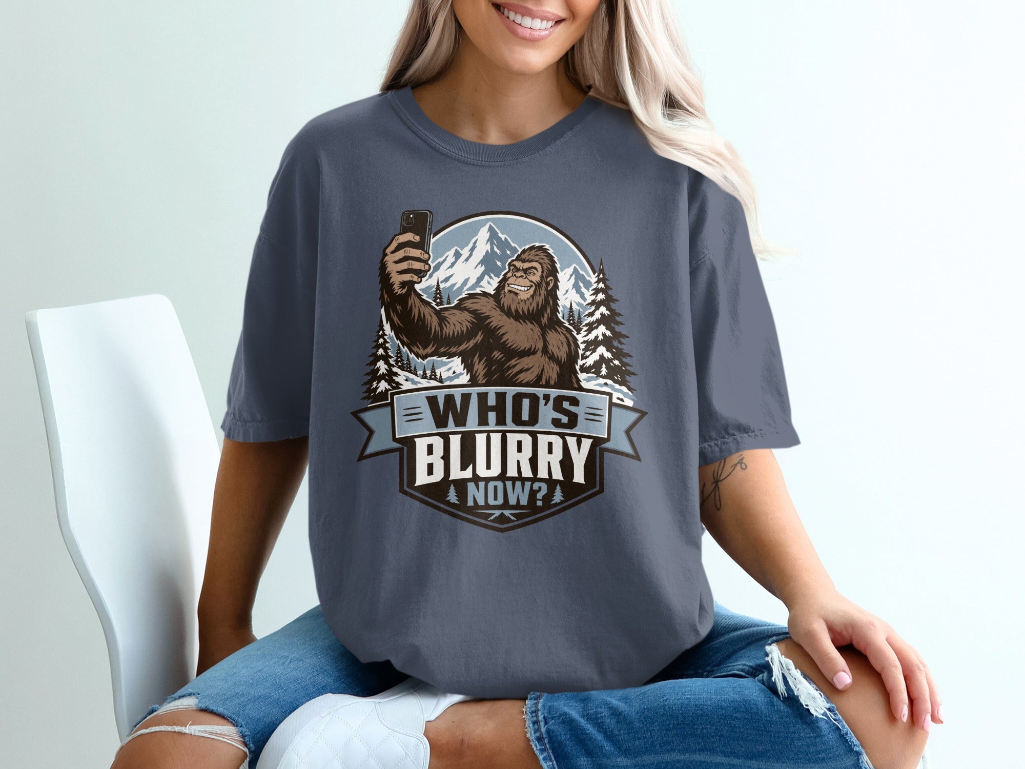 Bigfoot taking a selfie in snowy mountains with text "WHO'S BLURRY NOW?".