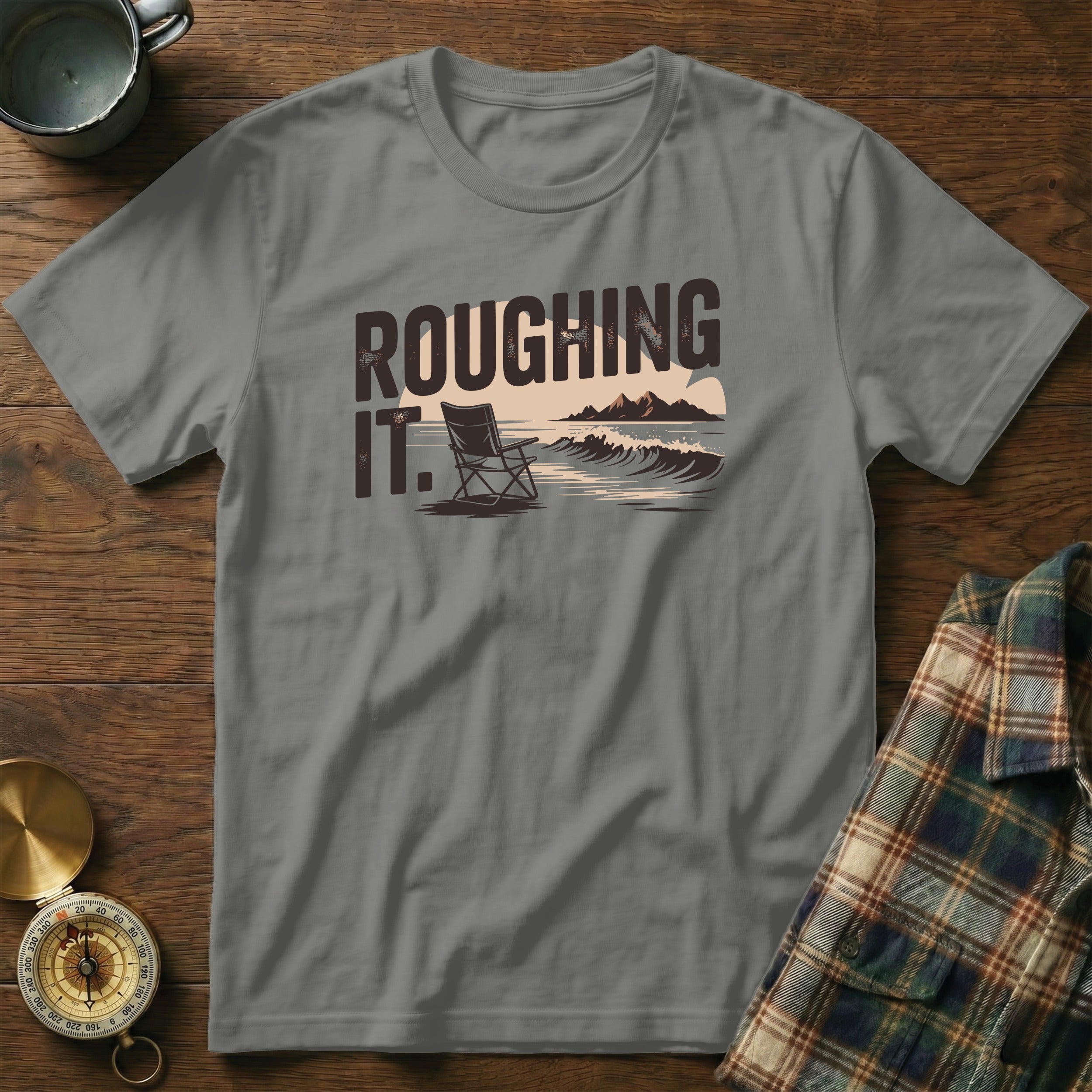 T-shirt with "ROUGHING IT" text and a camping scene with a chair and mountains.