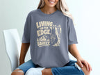 Grey t-shirt with text "LIVING ON THE EDGE BARELY" and a mountain goat.