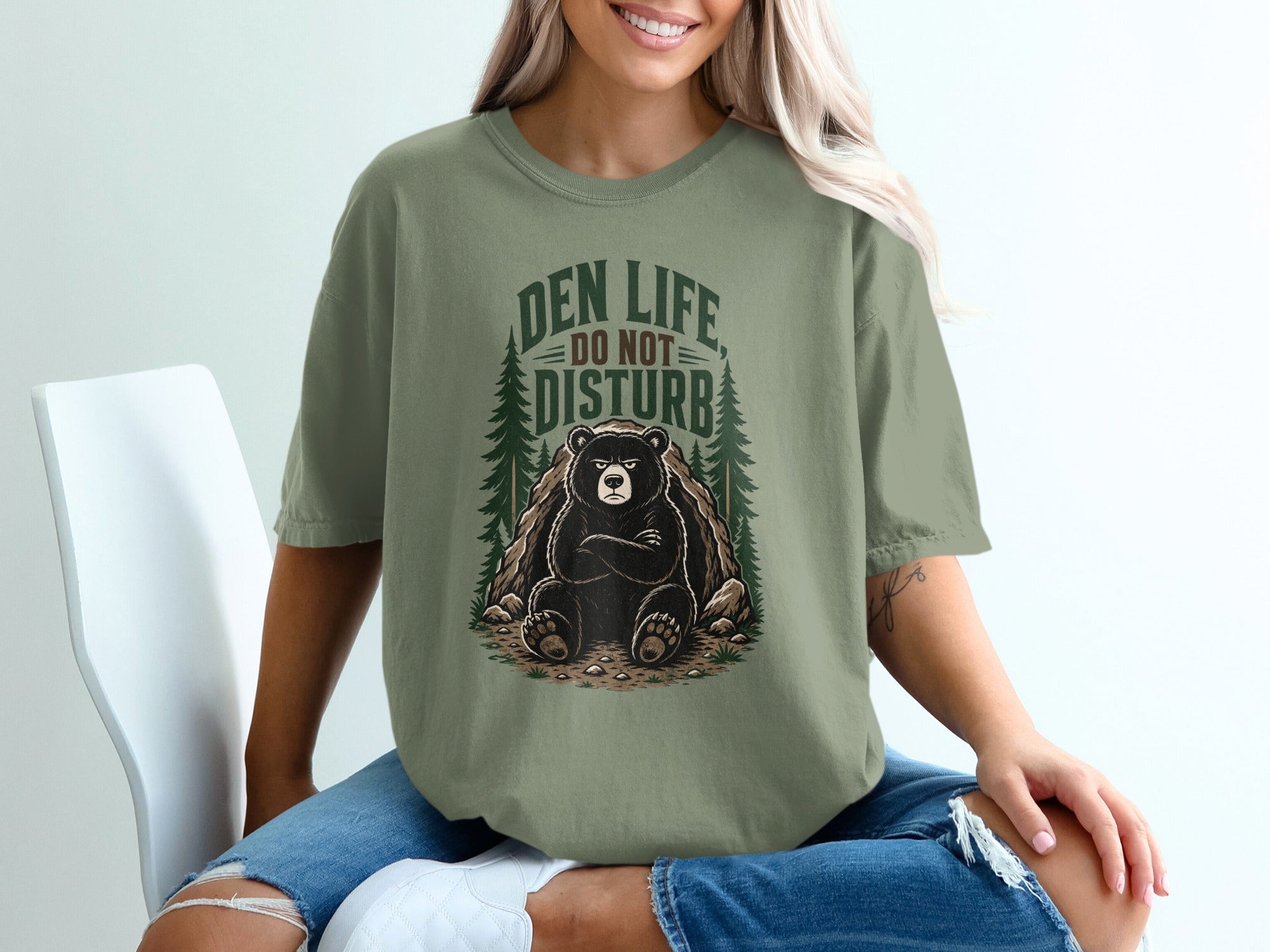 Green t-shirt with a sitting bear and "Den Life Do Not Disturb" text.