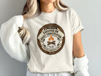 T-shirt with "Survived An Adult Conversation" merit badge design.