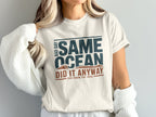Cream t-shirt with "Same Ocean, Bad Day, Did It Anyway" text and wave graphic.
