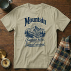Tan t-shirt with a blue graphic of mountains, trees, and text reading Mountain Sunrise hike. Sunset arrival.
