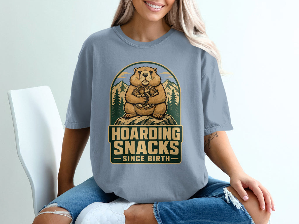 Groundhog design with text "Hoarding Snacks Since Birth" on a blue t-shirt.