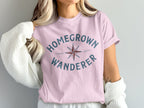 Pink t-shirt with "HOMEGROWN WANDERER" text and compass graphic.