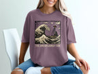 Purple t-shirt with "The Unexplained Tide" and wave/UFO graphic.