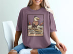 Graphic tee with surfing eagle wearing striped shirt and hat, text "UNBOTHERED COASTAL AMERICANA".