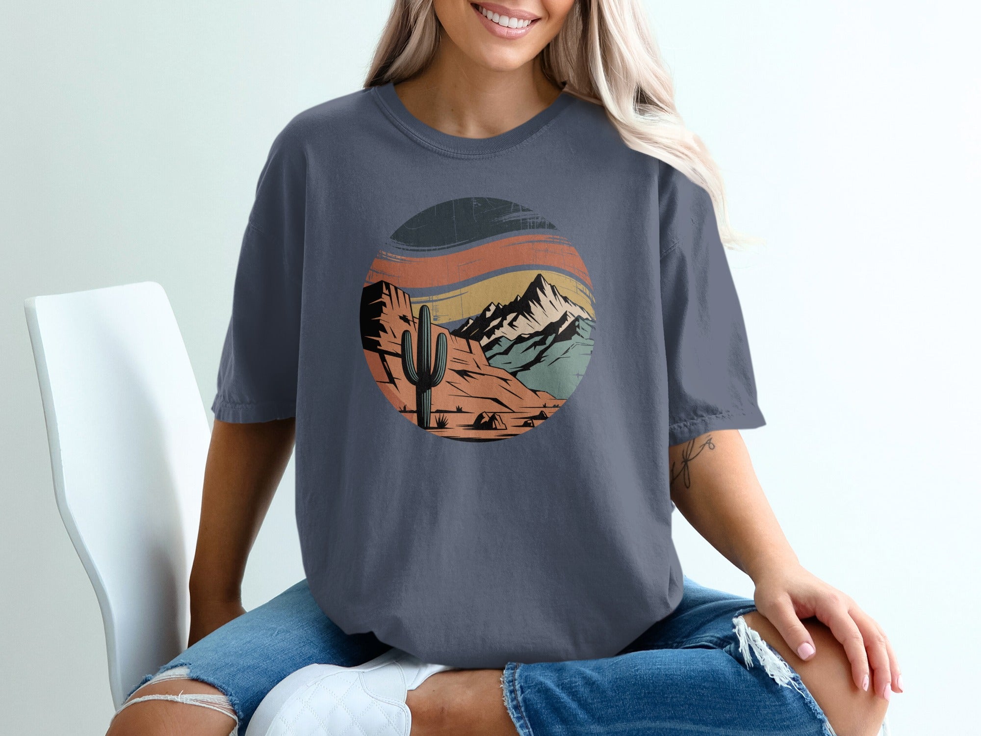 T-shirt with desert landscape graphic featuring cactus, mountains, and tent.