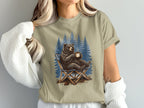 Bear sitting in a camping chair with a mug in a forest.