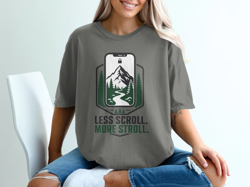 T-shirt graphic with phone displaying mountain landscape, "Less Scroll. More Stroll."