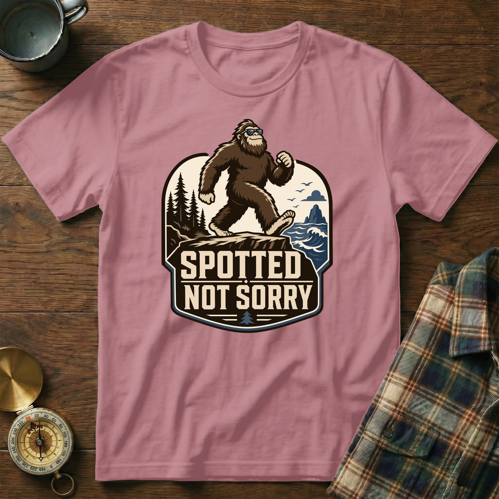 Bigfoot wearing sunglasses walks on a cliff while "Spotted Not Sorry" text is on a pink t-shirt.