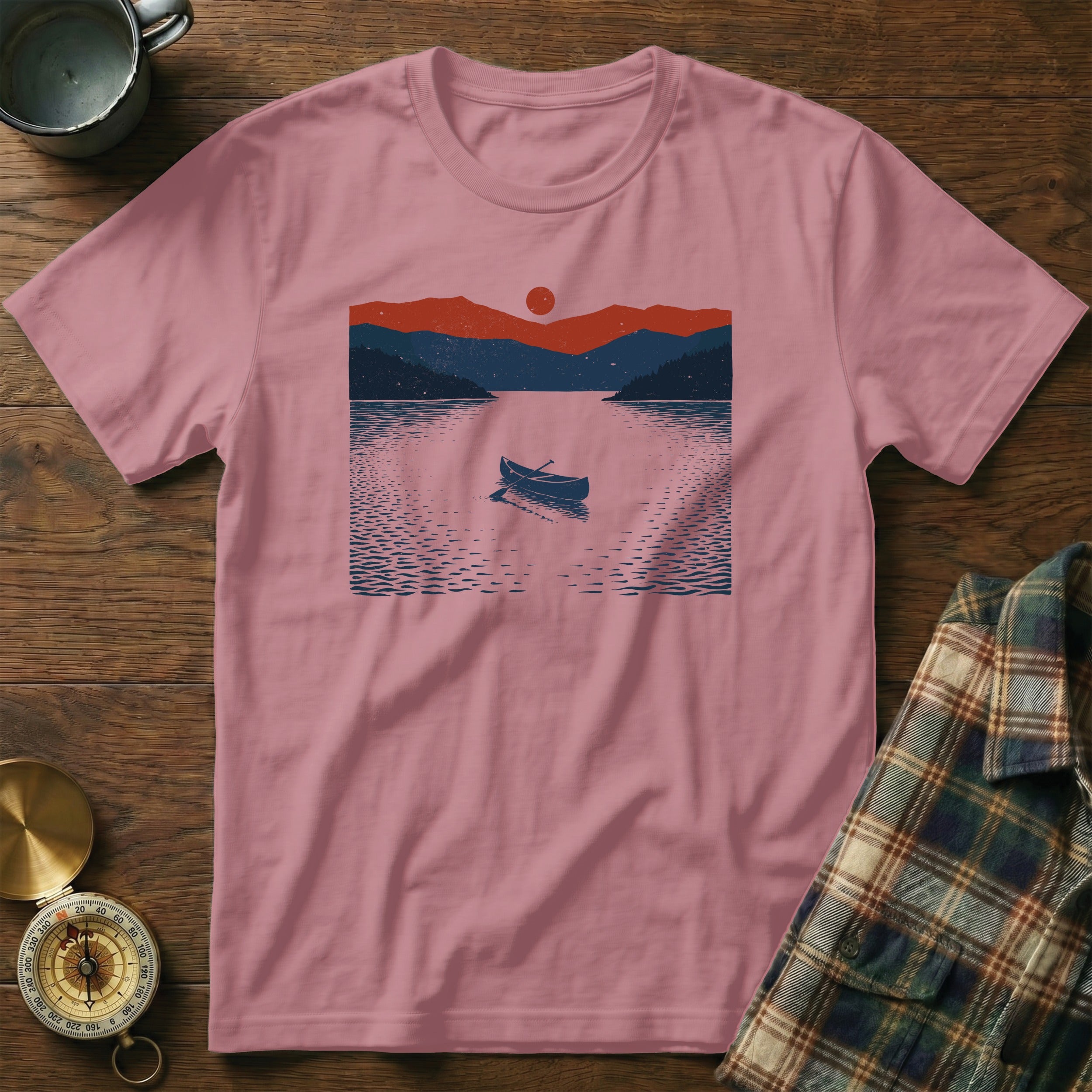 Pink t-shirt with a dark blue and red lake and mountain landscape graphic.