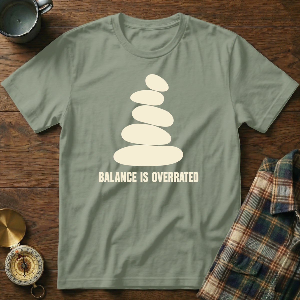 Green t-shirt with stacked stones and "BALANCE IS OVERRATED" text.